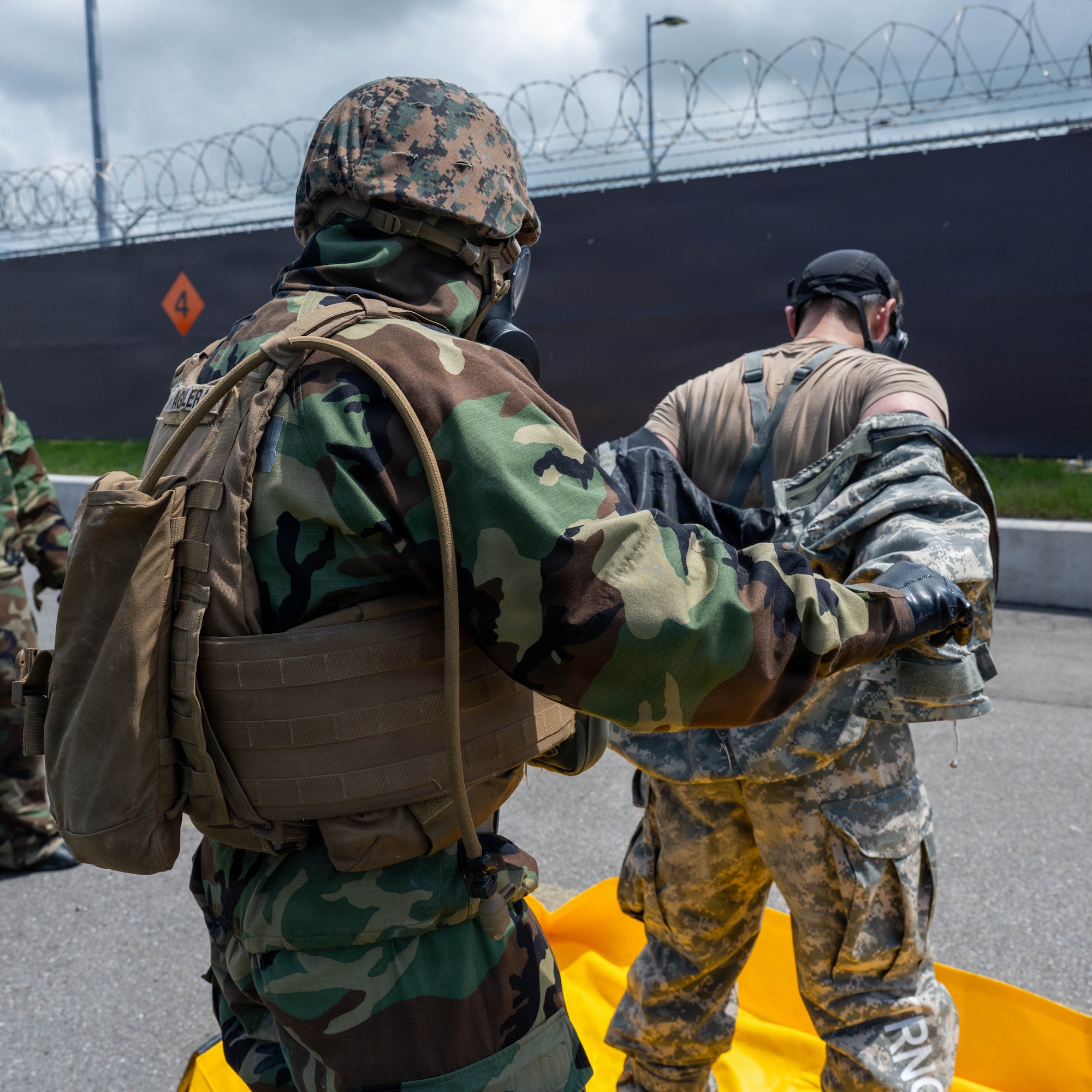 A U.S. Marine helps remove gear during simulated decontamination procedure.