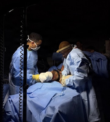 Hospitalman Anthony Rodriguez (left), surgical technologist, and Lt. Oluwakemi Mogaji (right),  physician assistant, both assigned to Expeditionary Resuscitative Surgical System (ERSS) 5 from Navy Medicine Readiness and Training Command Guam, provide aftercare to a simulated surgical patient under limited-light conditions inside a shipboard simulator during an ERSS course conducted at the Naval Expeditionary Medicine Warfighter Development Center (NEMWDC), June 16, 2026. The training replicates realistic, low-light operational environments to prepare medical personnel for expeditionary warfare deployment. NEMWDC provides specialized training to ensure medical readiness and optimize survivability in austere environments. (U.S. Navy photo by Petty Officer 2nd Class Moira Esquivel)