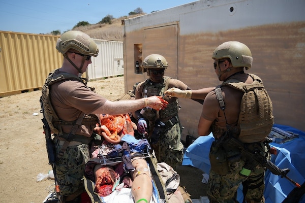 Hospitalman Anthony Rodriguez (right), surgical technologist assigned to Expeditionary Resuscitative Surgical System (ERSS) 5 from Navy Medicine Readiness and Training Command Guam, hands a surgical instrument to Lt. Cmdr. Cameron Paterson (left), general surgeon assigned to ERSS 5 from NMRTC Pearl Harbor, as Lt. Oluwakemi Mogaji, (center), assigned to ERSS 5 from NMRTC Guam, assists in a simulated field surgery during an Expeditionary Resuscitative Surgical System (ERSS) course conducted at the Naval Expeditionary Medicine Warfighter Development Center (NEMWDC), June 16, 2026. The evolution prepares the ERSS team to perform life-saving damage control surgery in austere, operational environments. The skill of the hospital corpsman as a surgical assistant is critical to the team’s success, enabling advanced medical intervention and increasing survivability on the battlefield. (U.S. Navy photo by Petty Officer 1st Class Trevin Perry)