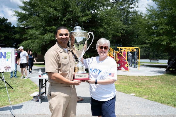 Capt. Darla Dietrich, commanding officer, Navy Medicine Readiness and Training Command Bethesda and Command Master Chief Aaron Paul pose for a photo with the 2026 NMRTC Bethesda Captain’s Cup trophy before announcing the winning team at Walter Reed National Military Medical Center, July 31, 2026. NMRTC Bethesda's mission is to maximize warfighter performance through optimized medical readiness tailored to operational requirements, enhance the readiness of the medical force to sustain expeditionary medical capability, and train and develop the Navy Medicine Force. (U.S. Navy photo by Mass Communication Specialist 2nd Class Alec Kramer)
