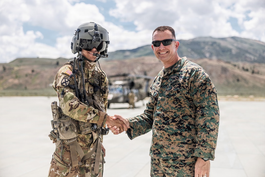 U.S. Marine Corps Col. Clarence Loomis, right, a New York native and incoming installation commander of Marine Corps Mountain Warfare Training Center, Marine Air Ground Task Force Training Command, coins U.S. Army Sgt. 1st Class Mason Burkhart, a Nevada native and a critical care flight paramedic and H-60 standardization instructor with Nevada Army National Guard, during Mountain Medicine 1-26 at MCMWTC, Bridgeport, California, July 15, 2026. MMED 1-26 develops technical skills and operational proficiency to operate in austere environments while strengthening multinational interoperability and readiness for future global operations. (U.S. Marine Corps photo by Cpl. Enge You)