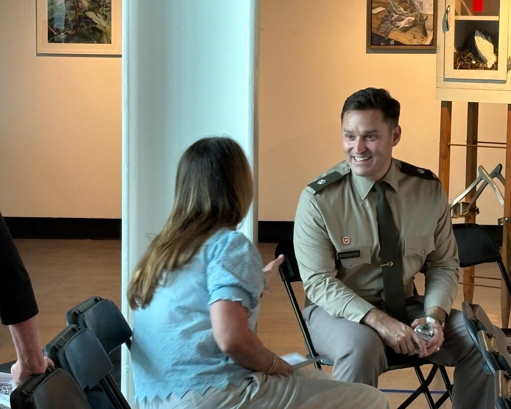 Military man talks sits in a chair and talks to woman about flooding