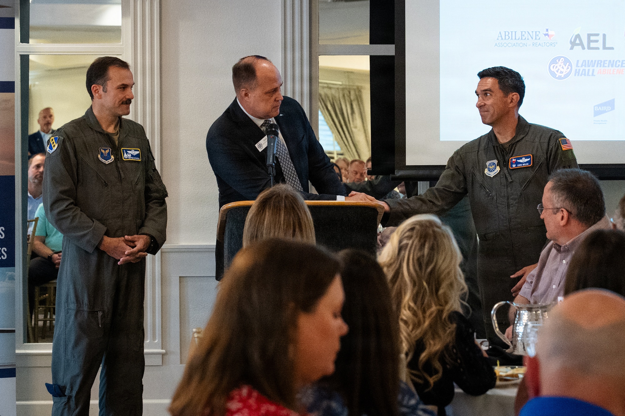 John Nichols, center, Military Affairs Council vice president, welcomes U.S. Air Force Col. Robert, “Ripper” Sturgill Jr., left, 7th Bomb Wing and installation commander, and Col. Christopher Welch, 317th Airlift Wing commander, to Abilene during a MAC luncheon in Abilene, Texas, July 30, 2026. Both Sturgill and Welch were introduced to civic leaders across Abilene as the newest commanders of the two wings that execute the “lift and strike” mission at Dyess Air Force Base. (U.S. Air Force photo by Senior Airman Jade M. Caldwell)