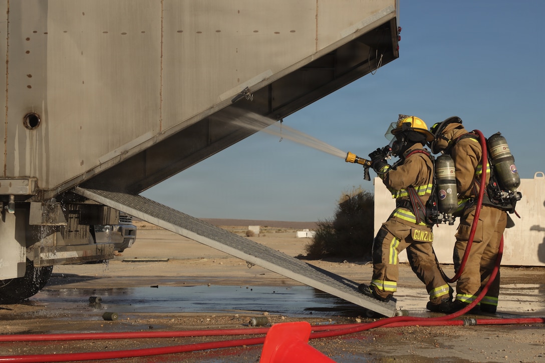 U.S. Marines with Marine Wing Support Squadron 373, Marine Aircraft Group 11, 3rd Marine Aircraft Wing, extinguish a controlled fire to increase readiness during Service Level Training Exercise 4-26 at the Strategic Expeditionary Landing Field, Marine Corps Air Ground Combat Center, Twentynine Palms, California, July 15, 2026. SLTE is a premier training event that ensures the Marine Corps remains a highly lethal, adaptable force capable of dominating the future multi-domain fight. (U.S. Marine Corps photo by Lance Cpl. DePaul)
