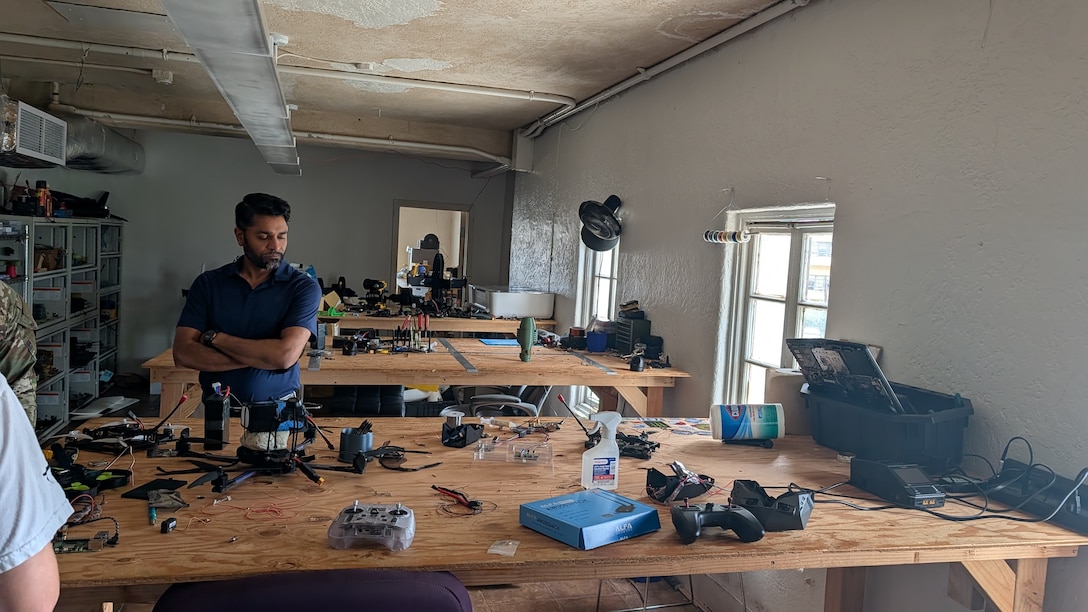 A man looks at drone components on a table.