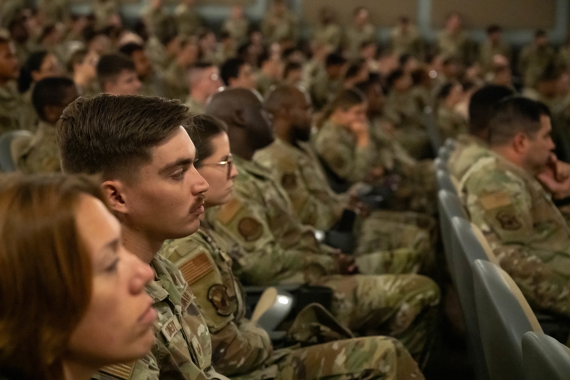 Airmen seated in a theater.