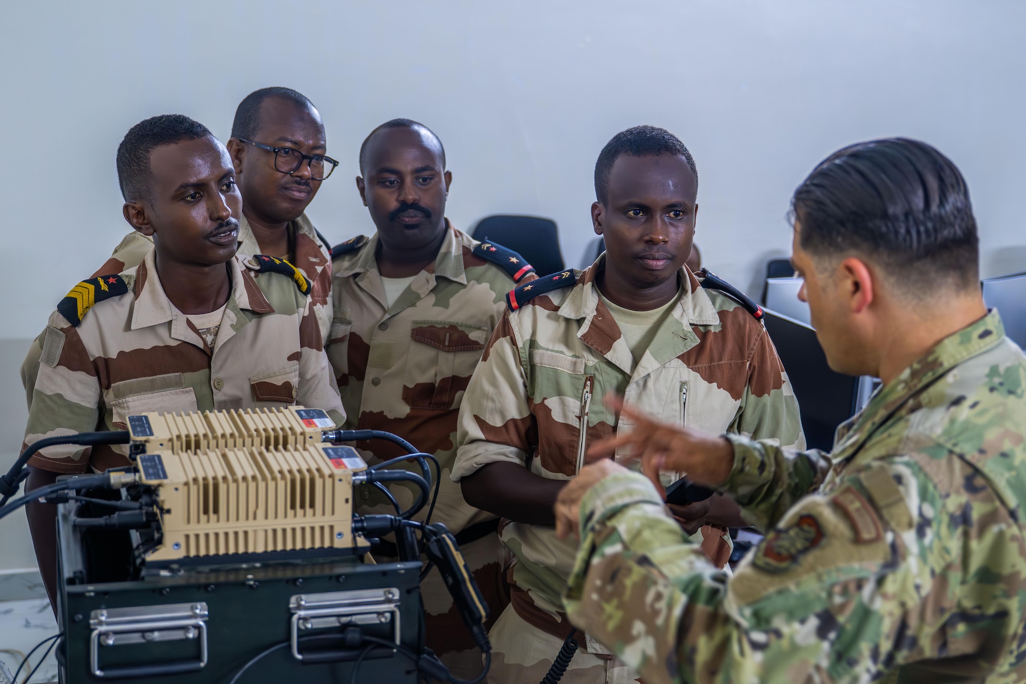 A military member instructs a group of four military members on radio procedures.
