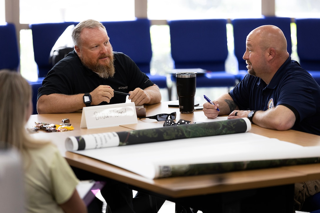 John Roberts, antiterrorism officer and critical infrastructure protection lead, and Michael Bush, installation emergency manager, both with Marine Corps Support Facility Blount Island, discuss a simulated drought and wildfire scenario during a facility incident readiness exercise Aug. 4, 2026, at Orange Park Town Hall in Orange Park, Florida. The tabletop exercise tested regional coordination among four Northeast Florida military installations and partner agencies. (U.S. Marine Corps photo by Dustin Senger)