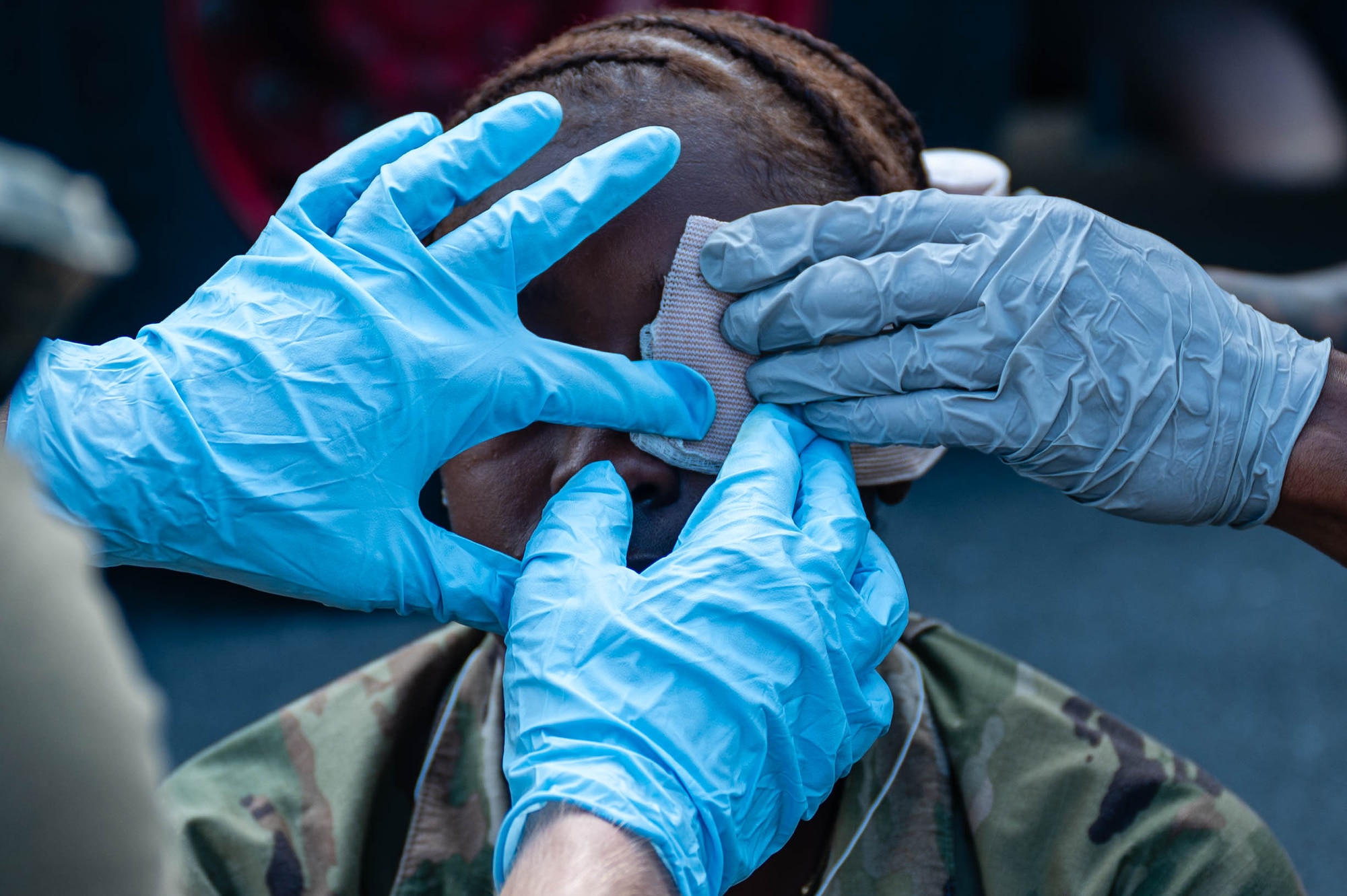 Service members apply bandages to a simulated patient.