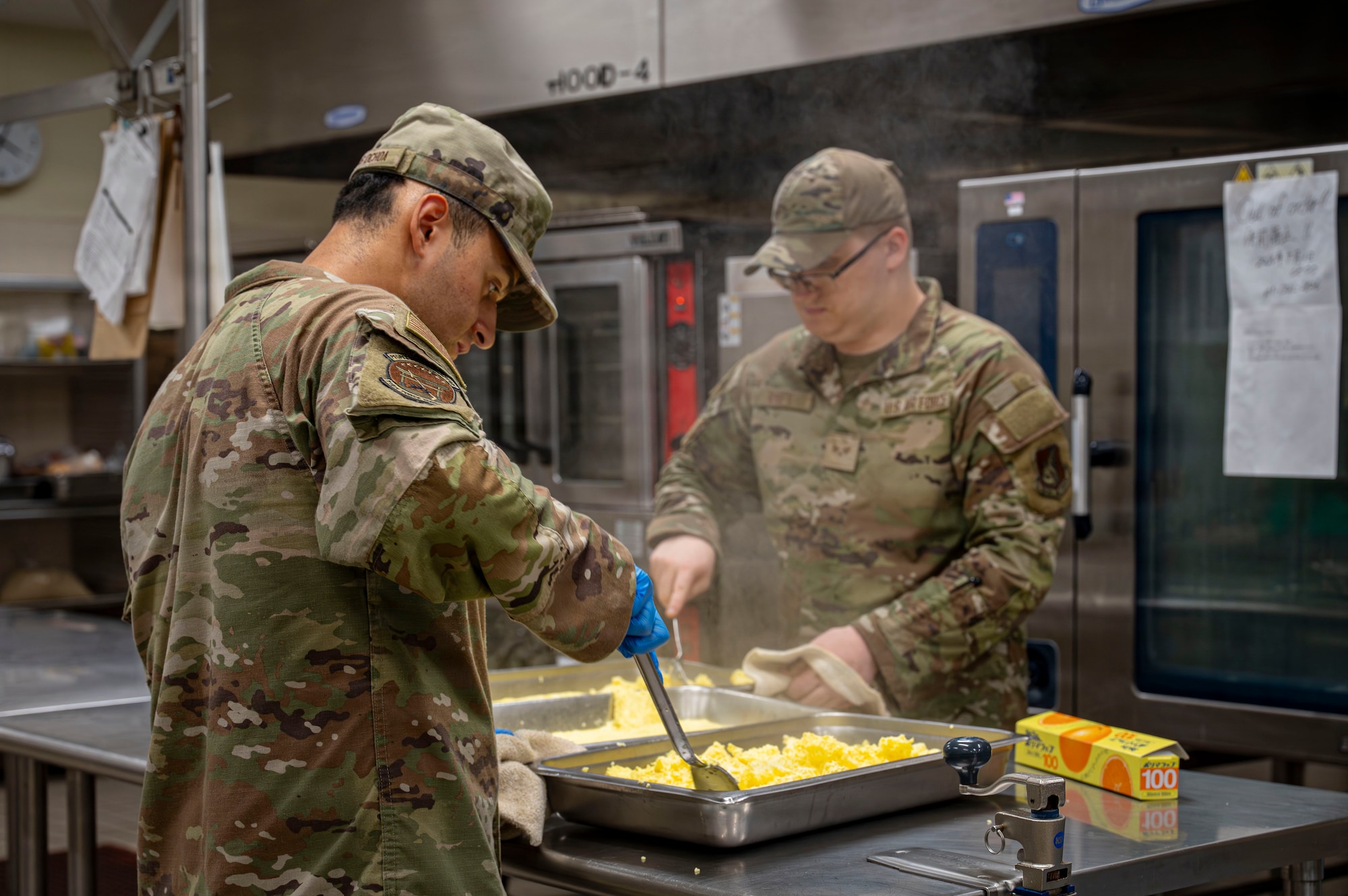 Two individuals stirring around cooked eggs