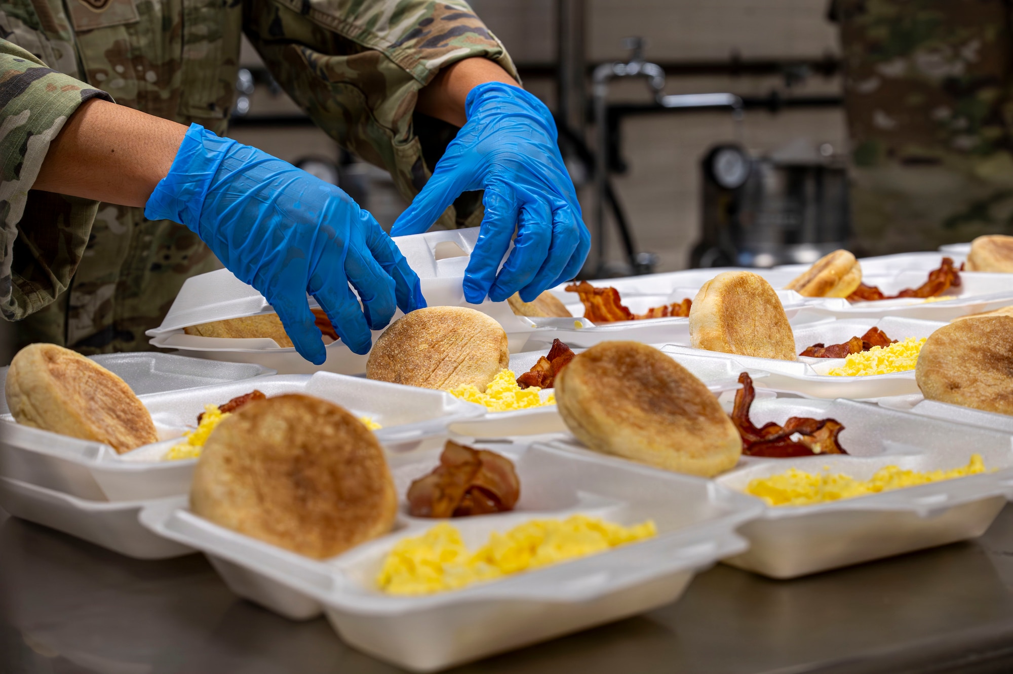 Gloved hands closing rows of food containers