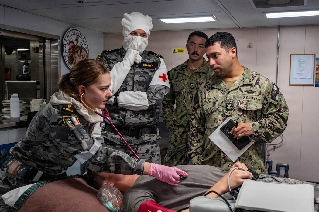 260718-N-IK052-1067 From left to right, Royal Australian Navy (RAN) Able Seaman Medic Sienna Williams, Lieutenant Elliot Heeney, nursing officer, RAN, U.S. Navy (USN) Lt. Alec Zamarripa, family medicine physician assigned to Pacific Partnership 2026 (PP26), and USN Hospital Corpsman 1st Class David Maldonado-Santiago, PP26 independent duty corpsman, work together to assess a simulated casualty in the senior sailors’ mess during an all-hands damage control drill aboard RAN amphibious Bay-class Landing Ship Dock (LSD) HMAS Choules (L100), at sea, July 18, 2026. Approximately 113 PP26 personnel from Australia, Canada, Germany, and the U.S. have embarked on Choules, which is providing transport and logistics support to the mission across multiple mission stops. Now in its 22nd iteration, the Pacific Partnership series is the largest annual multinational humanitarian assistance and disaster management preparedness mission conducted in the Indo-Pacific. Pacific Partnership works collaboratively with host and partner nations to enhance regional interoperability and disaster response capabilities, increase security and stability in the region, and foster new and enduring friendships in the Indo-Pacific. (U.S. Navy photo by Ensign Caroline H. Lui)
