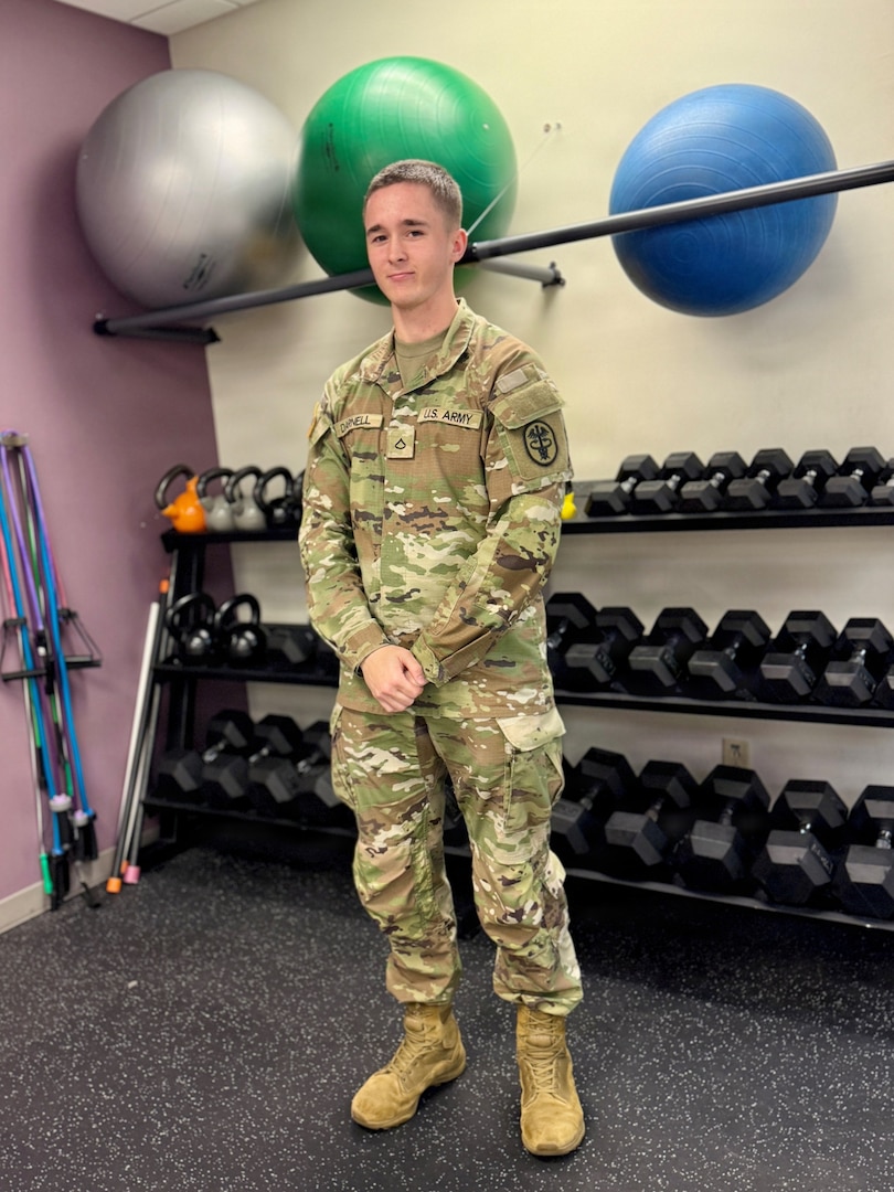 Soldier Therapist poses in front of a rack of dumbells.