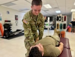 Soldier Therapist immobilizes a patients shoulder in a clinical setting.