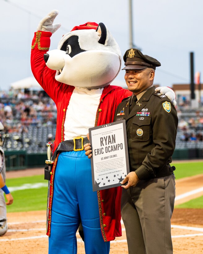 Smiling man wears a military uniform and holds a plaque