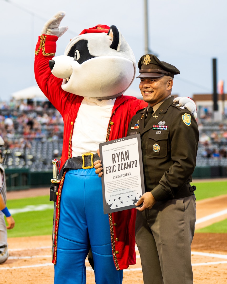 Smiling man wears a military uniform and holds a plaque