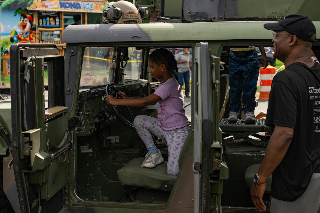 Child sits in the seat of a military vehicle.