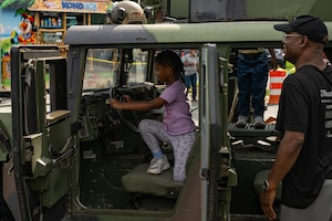 Child sits in the seat of a military vehicle.