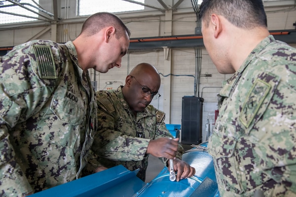 U.S. Navy Gunner’s Mate 1st Class Jason Muoio, left, and U.S. Navy Mineman 1st Class Hongji Liu, right, observe U.S. Navy Mineman 2nd Class Asaberry Coleman, assigned to Navy Reserve (NR) Navy Munitions Command Pacific (NMCPAC) Mine Assembly Unit Okinawa (MAU OKI), tighten bolts on a tail fin to an inert 2,000-pound Mark 65 Quickstrike mine during a mine assembly training evolution at Naval Weapons Station Seal Beach, California, July 12, 2026. NR NMCPAC MAU OKI conducted the assembly training to evaluate munitions readiness and strengthen reserve force integration within the U.S. Pacific Fleet area of operations. (U.S. Navy photo by Mass Communication Specialist 1st Class Bryan Ilyankoff)