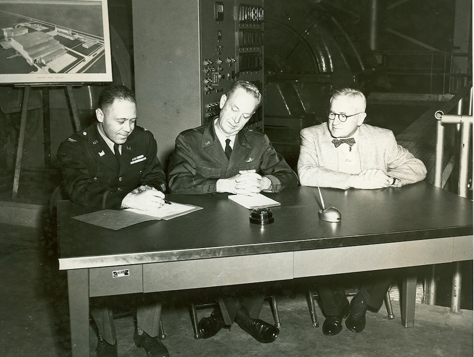 Col. L.E. Cox, engineer with the Tullahoma District of the U.S. Army Corps of Engineers, left, prepares to turn the Arnold Engineering Development Center Engine Test Facility Exhaust Compressor Building over to then-AEDC Commander Brig. Gen. Samuel Harris, center, during a Nov. 30, 1953, ceremony at the Center. Harris then indorsed the building and equipment over to Thomas Farrell, managing director of Arnold Research Organization, right. ARO was the corporation established to maintain and operate AEDC. In the background is one of the six compressors contained within the Exhaust Compressor Building which, up to that point, was the largest single unit completed at AEDC. (U.S. Air Force photo)