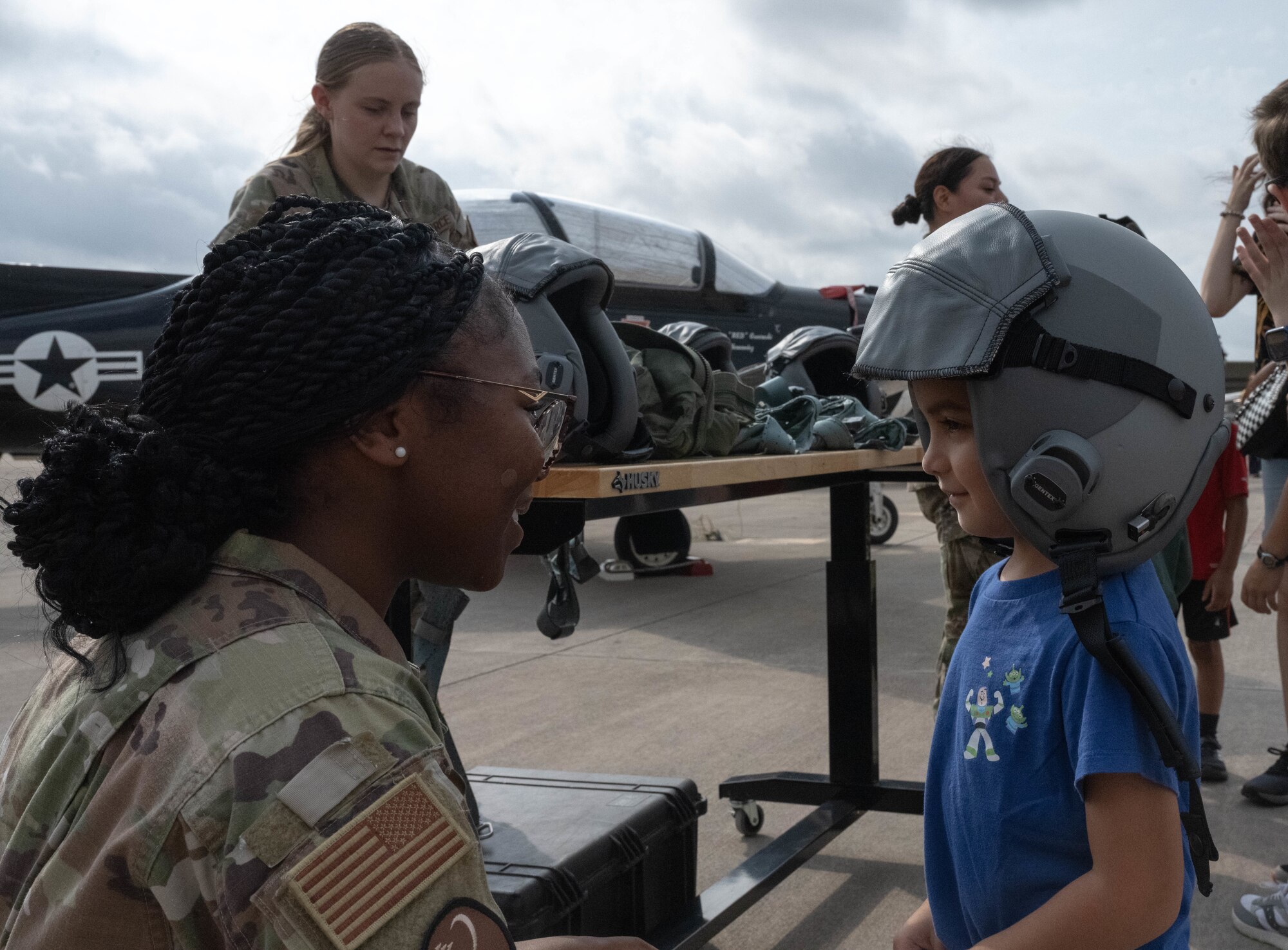 U.S. Air Force Airman 1st Class Imajanae Moses, 47th Operations Support Squadron air crew flight equipment specialist, places a flight helmet atop a Tiger for a Day participant at Laughlin Air Force Base, Texas, August 5, 2026. Partcipants were able to try on various flight equipment during the Tiger for a Day event. (U.S. Air Force photo by Airman 1st Class Darryl Keith)