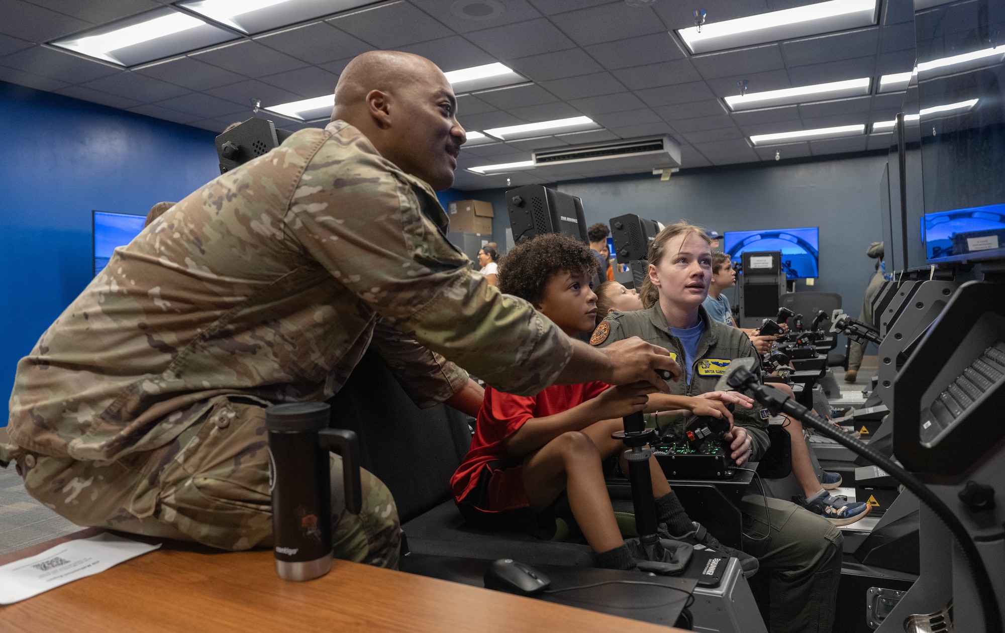 From left, U.S. Air Force Staff Sgt. Arthur Johnson, 47th Contracting Squadron contracting specialist, and 1st Lt. Brita Ilustre, 85th Flying Training Squadron instructor pilot, right, assists a participant of Tiger for a Day with the controls in a flight simulator event at Laughlin Air Force Base, Texas, Aug. 5, 2026. Flight simulators aid in the development of student pilots enrolled in Undergraduate Pilot Training. (U.S. Air Force photo by Airman 1st Class Darryl Keith)