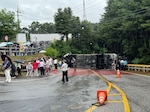 A tour bus sits overturned on a roadway in Paju, Republic of Korea, June 20, 2026. Off-duty U.S. Airmen and Soldiers sprang into action after the bus overturned, assisting injured passengers until emergency services arrived.