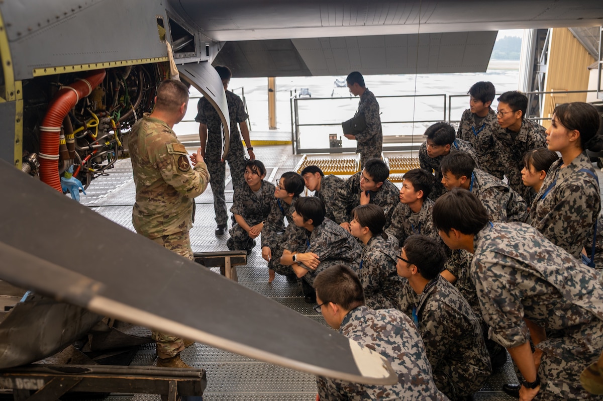 Japanese Airmen look at an aircraft engine.