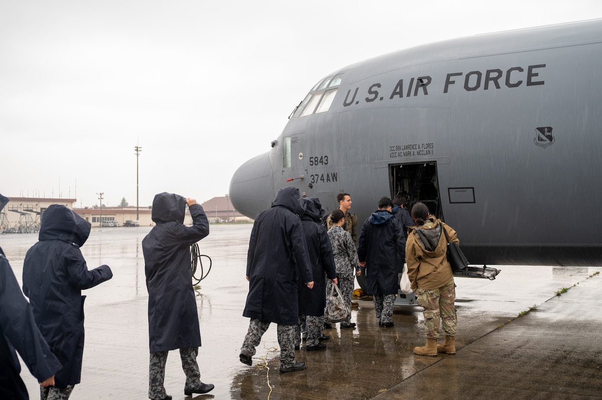 Japanese Airmen enter an aircraft in the rain.