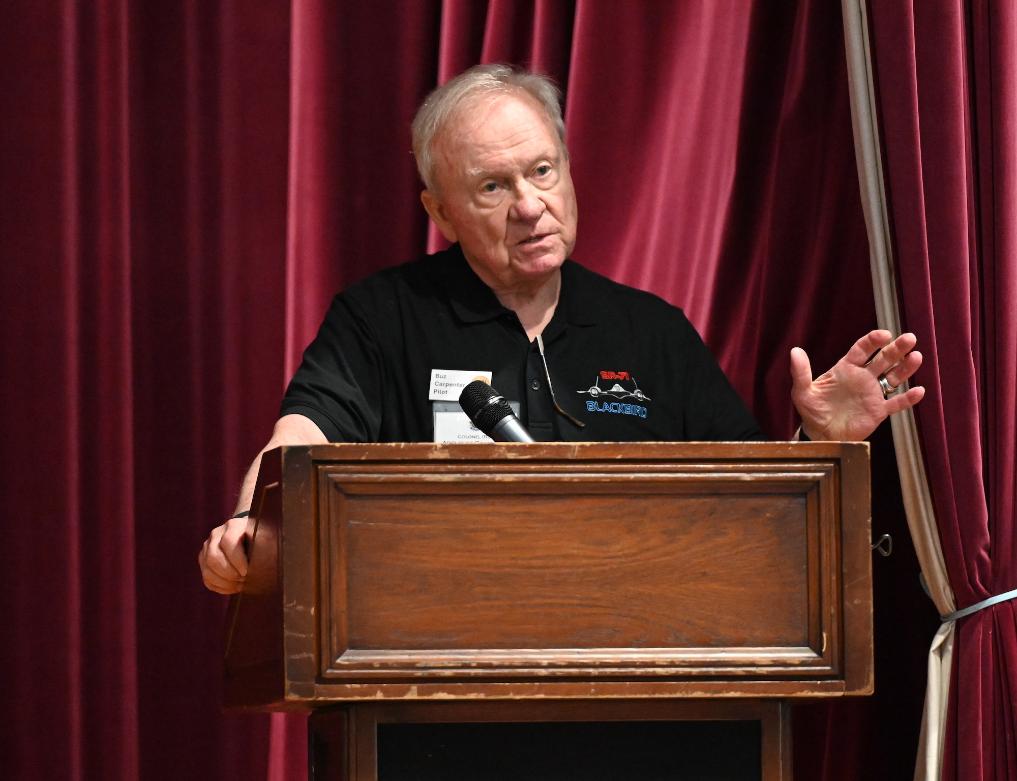 U.S. Air Force Col. (ret.) Buz Carpenter, former SR-71 Blackbird instructor pilot, shares some of his memories of flying the supersonic aircraft with the audience at RAF Mildenhall, England, July 27, 2026. Carpenter and other SR-71 veteran pilots, aircrew and maintainers, along with their family members, received mission briefings and a tour of the base, including hangars where they once worked, and static displays. The Blackbird was assigned to Detachment 4, 9th Reconnaissance Wing, out of RAF Mildenhall from 1976 to 1990, and 2026 marks the 50th anniversary of its arrival here. (U.S. Air Force photo by Karen Abeyasekere)