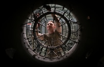 A military member works on the back of an engine