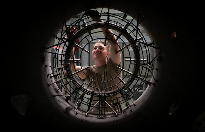 A military member works on the back of an engine