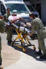 U.S. Navy Hospital Corpsman 3rd Class Neko Henderson, left, and Hospital Corpsman 2nd Class Melodie Abell move a simulated casualty from an ambulance into U.S. Naval Hospital Rota during a mass casualty exercise at Naval Station Rota, Spain, June 25, 2026. The exercise tested patient transfer procedures and coordination between emergency responders and hospital personnel. (U.S. Navy photo by Hospital Corpsman 2nd Class Ahmi Atsina)