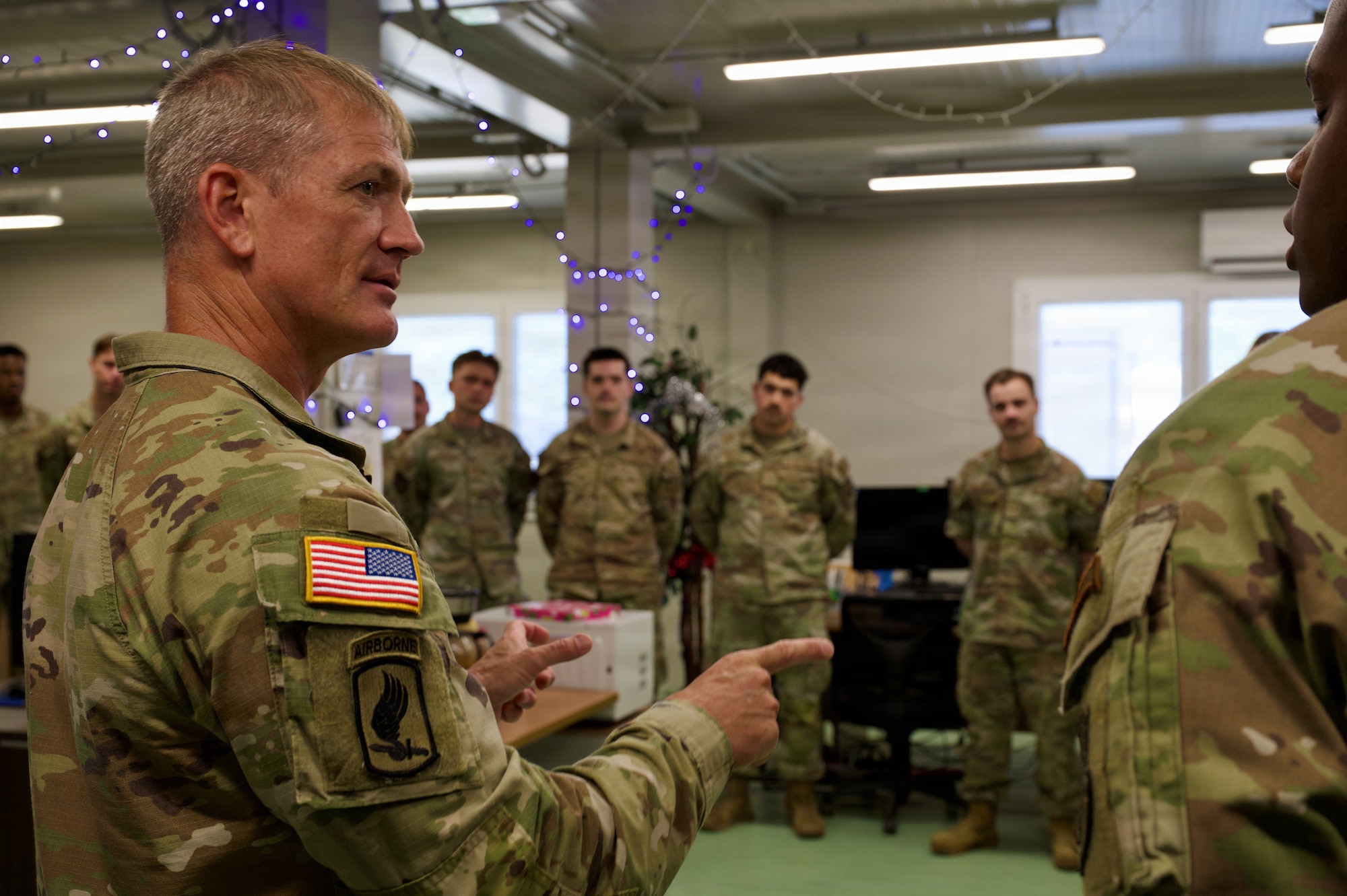 An army commander speaks with a room filled with airmen.