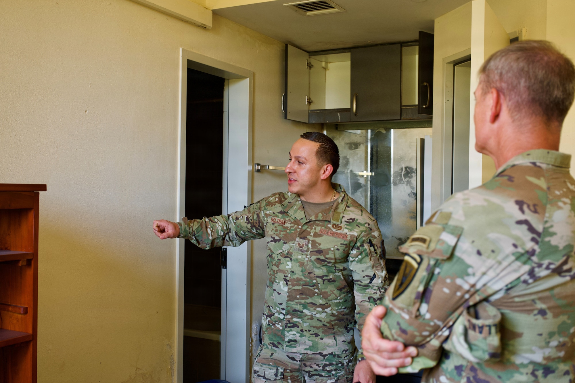 One service member gives another service member a tour of the dorms on base.