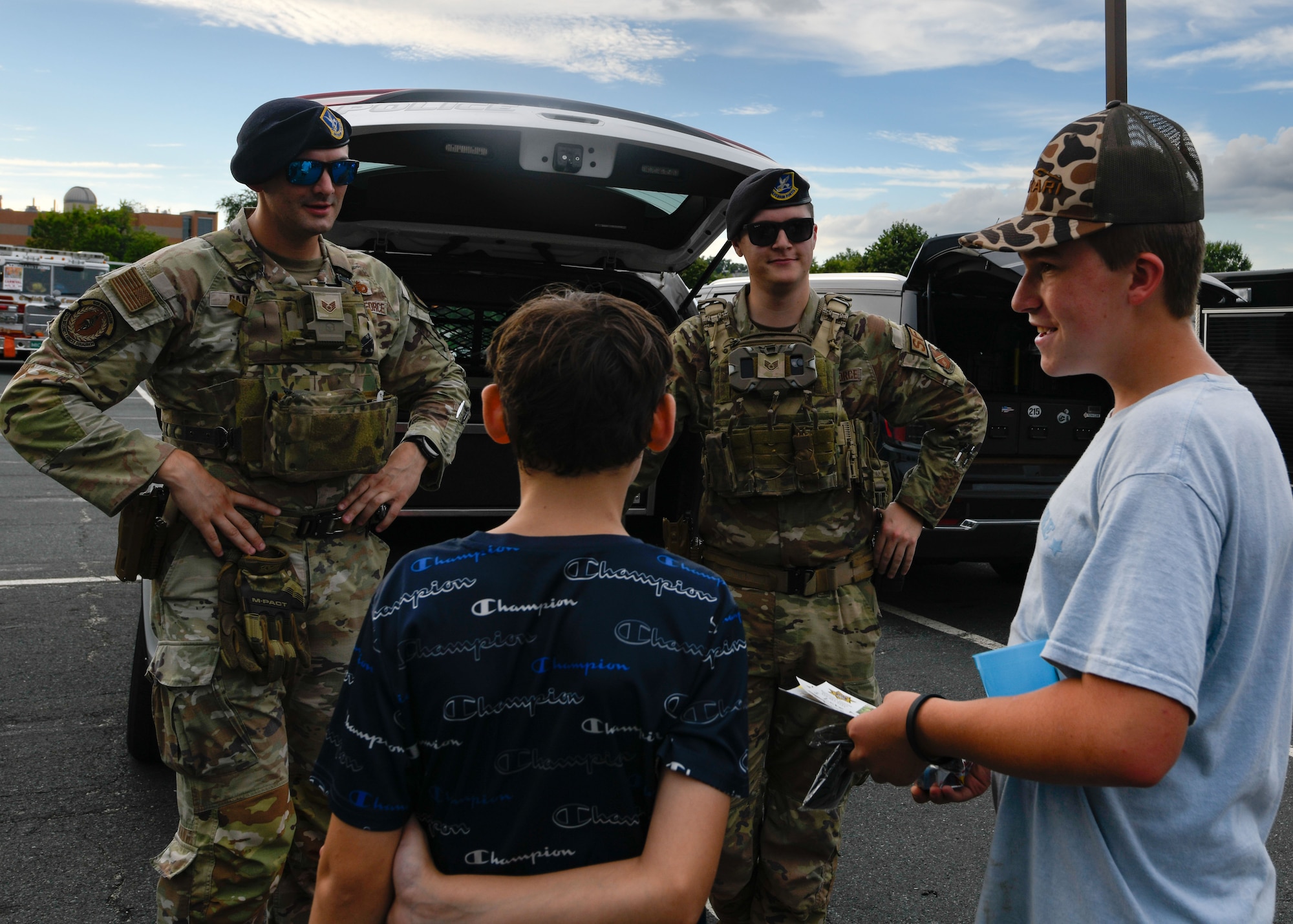 U.S. Air Force Staff Sgt. Travis A. Radle, left, 316th Security Forces Squadron police services noncommissioned officer in charge, and Staff Sgt. Ayden J. Weier, 316th Security Forces Squadron confinement noncommissioned officer in charge, interact with local youth