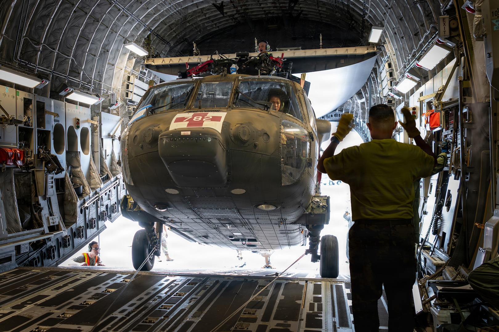 U.S. Army Chief Warrant Officer 4 Hau Okada, a Hawaii Army National Guard pilot, maneuvers a UH-60M Black Hawk helicopter aboard a Hawaii Air National Guard C-17 Globemaster III assigned to the 204th Airlift Squadron as U.S. Army 1st Sgt. Christopher Pacheco, a Hawaii Army National Guard senior mechanic and standardization instructor, guides the aircraft from atop its folded rotor system during upload operations at Hilo International Airport, July 31, 2026.