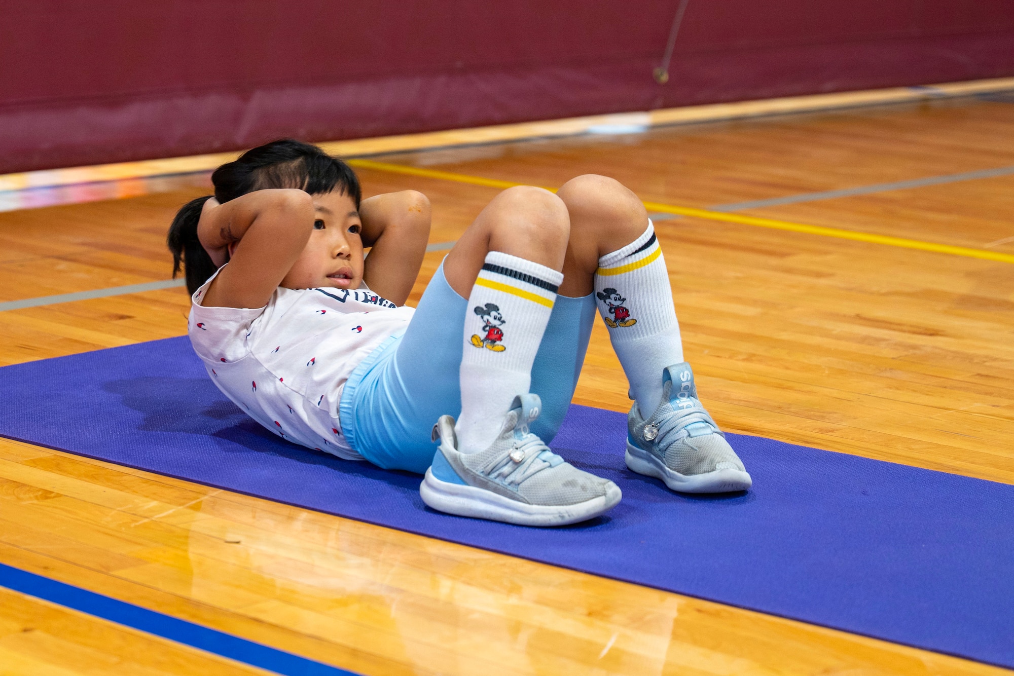 Student does sit-ups on a basketball court.