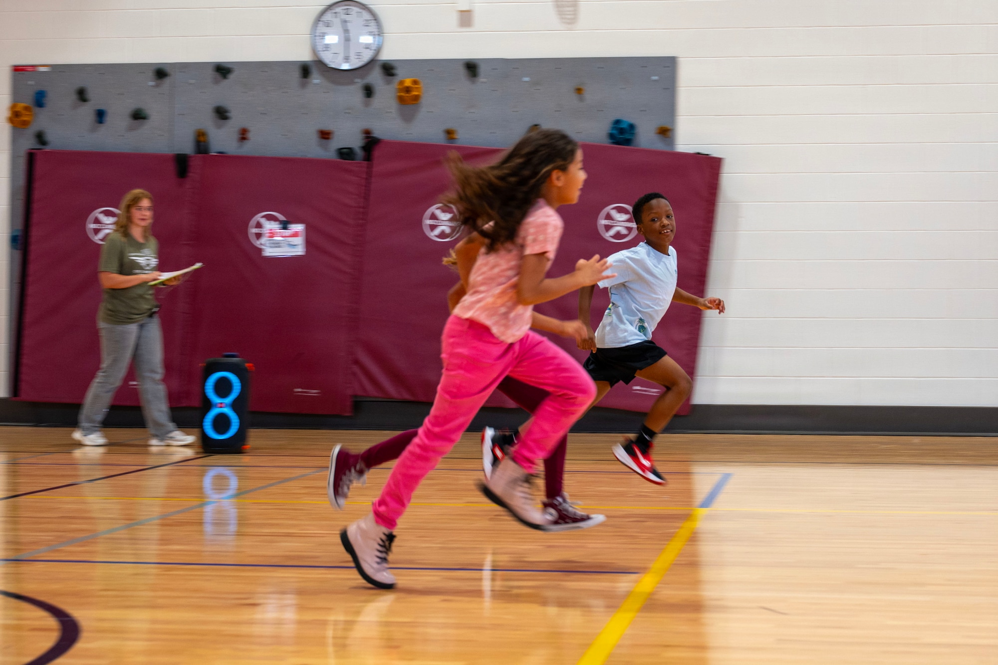 Students run across a basketball court.
