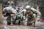 Infantry OSUT trainees, Alpha Company, 2nd battalion, 58th Infantry Regiment, 198th Infantry Brigade, navigate an obstacle while transporting a litter casualty during a combat lifesaver course lane at Fort Benning, GA, February 11, 2023. (U.S. Army  photo by Capt. Stephanie Snyder)