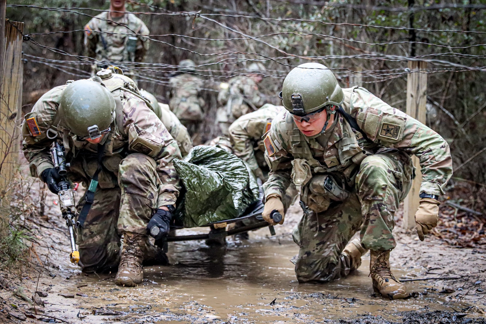 Infantry OSUT trainees, Alpha Company, 2nd battalion, 58th Infantry Regiment, 198th Infantry Brigade, navigate an obstacle while transporting a litter casualty during a combat lifesaver course lane at Fort Benning, GA, February 11, 2023. (U.S. Army  photo by Capt. Stephanie Snyder)