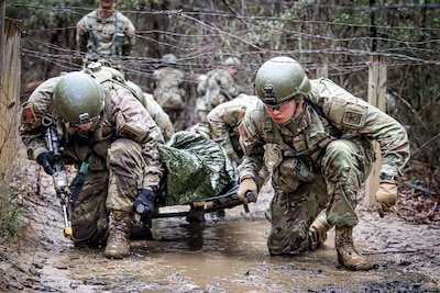 Infantry OSUT trainees, Alpha Company, 2nd battalion, 58th Infantry Regiment, 198th Infantry Brigade, navigate an obstacle while transporting a litter casualty during a combat lifesaver course lane at Fort Benning, GA, February 11, 2023. (U.S. Army  photo by Capt. Stephanie Snyder)