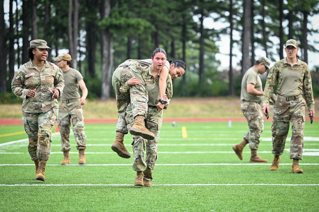 An Airmen carries another Airmen on her their shoulders while running