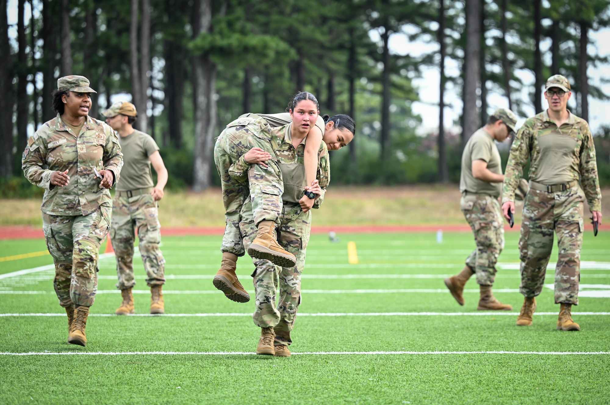 An Airmen carries another Airmen on her their shoulders while running