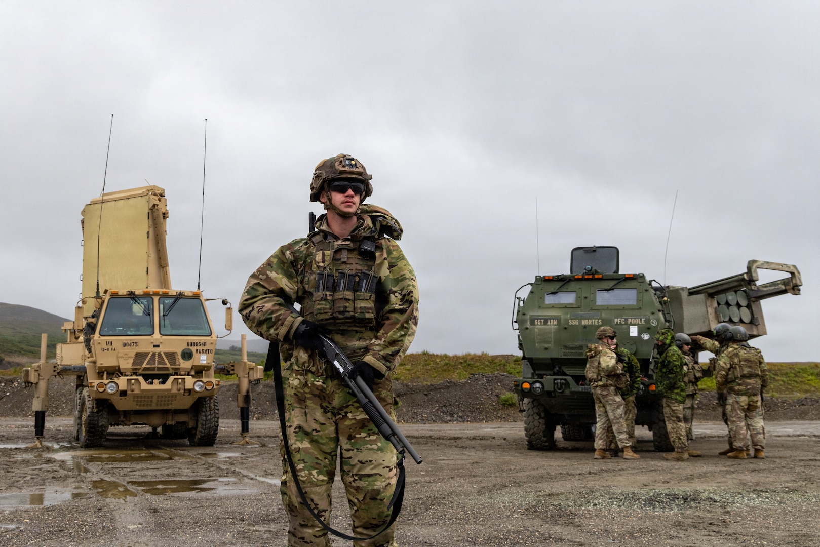 U.S Army Sgt. Blake Miller, 1st Squad leader assigned to 1st Battalion, 5th Infantry Regiment, 1st Mobile Brigade Combat Team (Air Assault), 11th Airborne Division pulls security in front of a AN/TP Q-53 Radar System and a High Mobility Artillery Rocket System assigned to the 17th Long Range Fires and Effects Brigade during Operation TUNDRA MERLIN near Nome, Alaska, Aug. 4, 2026. These Soldiers were deployed alongside the AN/TP Q-53 and HIMARS during TUNDRA MERLIN to demonstrate the joint forces' ability to rapidly deploy and seamlessly integrate combat equipment and personnel across the Arctic in defense of the Homeland and its approaches. (U.S. Air Force photo by Staff Sgt. Christopher Chen)