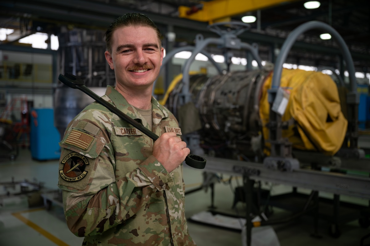 A military member poses with a wrench