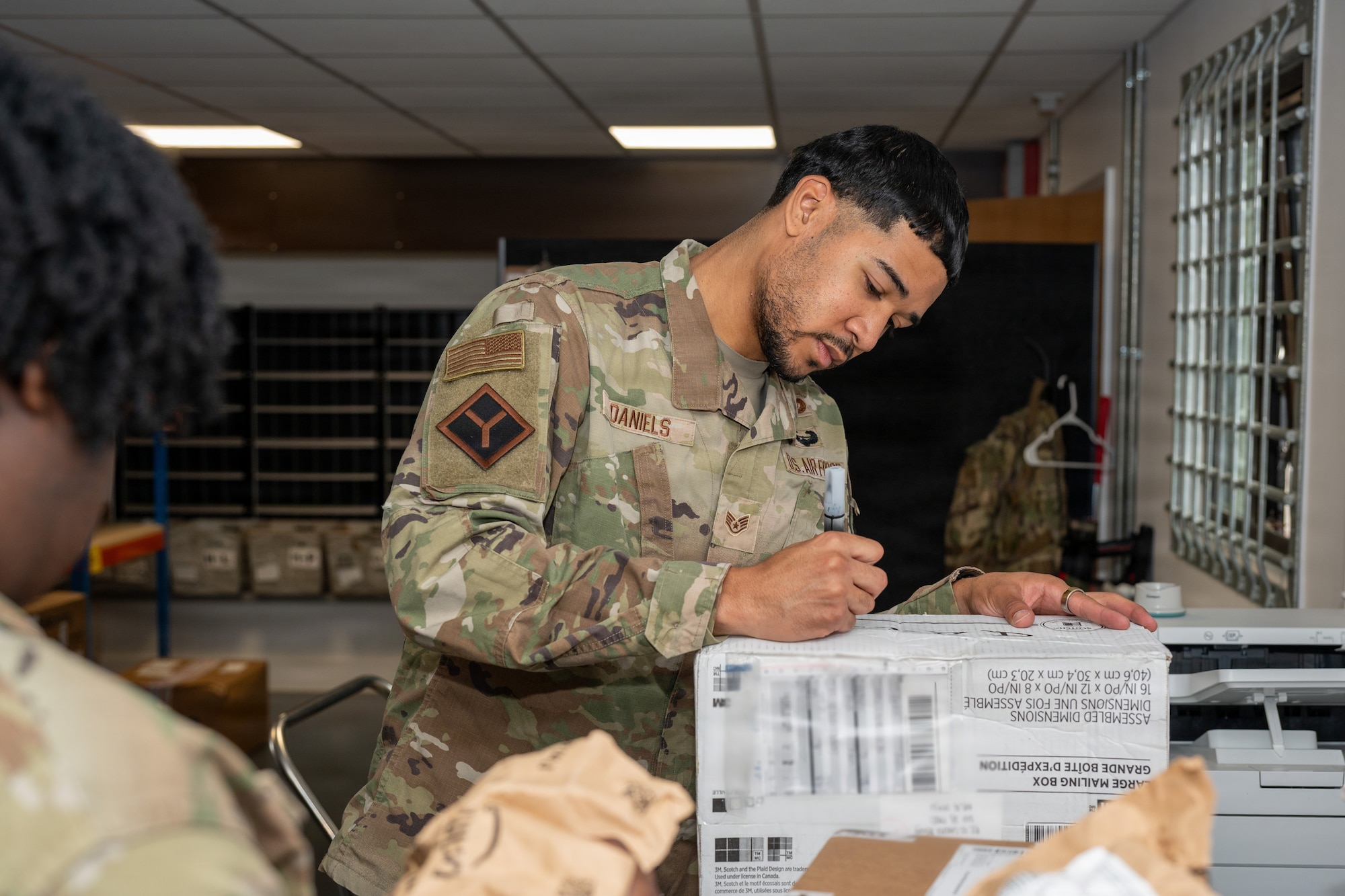 U.S. Air Force Staff Sgt. Jahrin Daniels, 422nd Air Base Squadron military postal clerk, labels an incoming package at the RAF Fairford Post Office, England, Aug. 5, 2026. The post office processes personal and official mail while providing package shipping and receiving services. (U.S. Air Force photo by Senior Airman Adam Enbal)