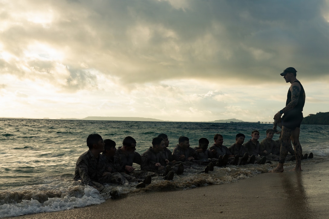 U.S. Marines and Sailors with 12th Littoral Combat Team, 12th Marine Littoral Regiment, 3rd Marine Division, listen to instruction during a culminating event of a Combat Medical Course at Camp Courtney, Okinawa, Japan, July 24, 2026. The CMC is key to improving tactical combat casualty care by building the confidence and resilience needed to perform lifesaving trauma medicine in realistic conditions. (U.S. Marine Corps photo by Lance Cpl. David Posada)
