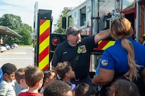 Fireman shows a group of children equipment on a fire truck