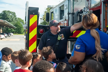 Fireman shows a group of children equipment on a fire truck